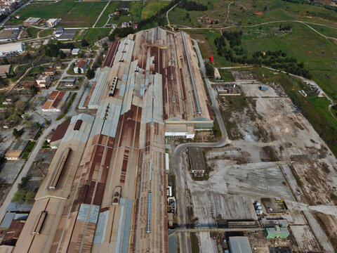 Aerial view of an expansive industrial complex under the golden light, with rusted rooftops contrasting against the stark concrete, Thessaloniki, Thessaloniki, Greece.