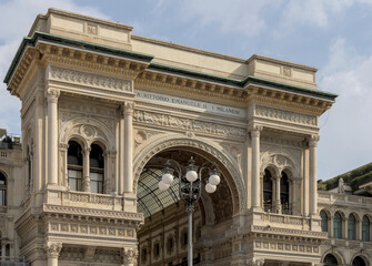 Obraz premium Galleria Vittorio Emanuele II Exterior in Milan Crowded plaza in front of a historic shopping arcade in Milan, capturing vibrant city life, tourism, and iconic architecture.