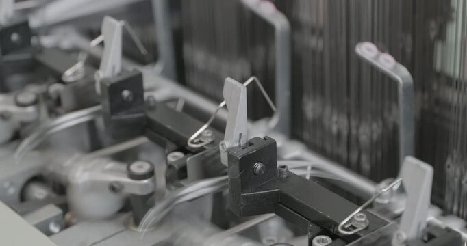 Spinning equipment, weaving machine, the jacquard loom is working. The parts of the mechanism move rhythmically, performing reciprocating movements. Close-up handheld shot, real time speed.