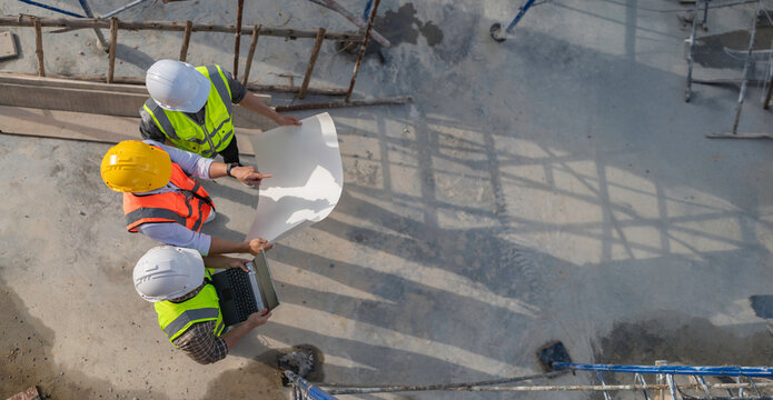 Three Asian engineer working at site of a large building project,Work overtime at construction site,Team of engineer discus at site,The architect, supervisor, and foreman meet to discuss the design