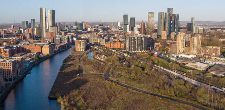 Aerial panorama over Pomona Island featuring River Irwell, Metrolink tram tracks, and the expanding skyscraper cluster in Manchester, UK.