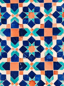 Authentic Moroccan zellige tile mosaic pattern featuring intricate geometric designs in vibrant blue, turquoise, and terracotta colors on a white background