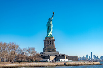 Fototapeta premium Rear view of the Statue of Liberty standing on Liberty Island under a clear blue sky in New York Harbor, USA. Iconic national landmark, travel destination and freedom concept.