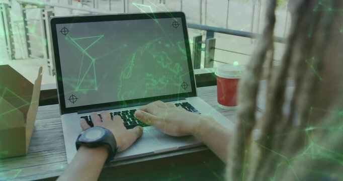 Man typing on balcony laptop, activating green holographic globe overlay while testing tech project