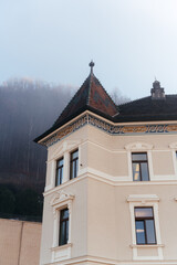 Obraz premium Elegant European buildings with classic architecture set against scenic mountains and clear blue sky. Charming urban atmosphere with historic details and picturesque alpine landscape 