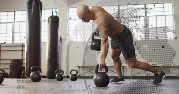 Vertical video: Entering gym, shirtless man rowing kettlebells at center, keeping tight core