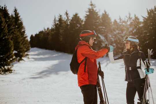 Skiers give thumbs up at the ski resort on a sunny day surrounded by trees