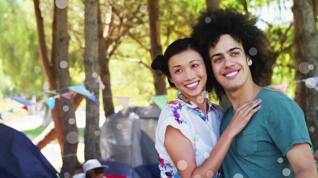 Vertical video: Cam closing, pair posing and pointing at camp, guitar, floral top, shorts, teal tee