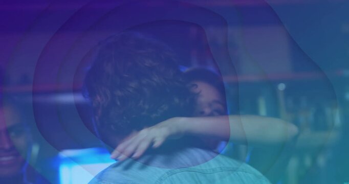 Denim man receiving greeting hug after hand bump in club, blue light pulsing across shoulder