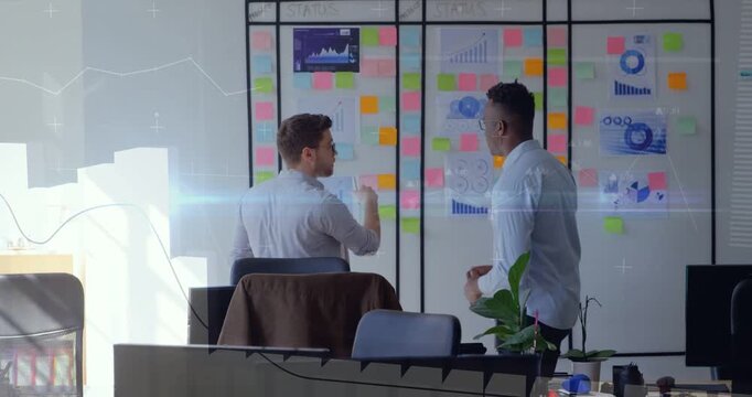 Two coworkers pointing at business board, stepping closer and comparing charts to set priorities