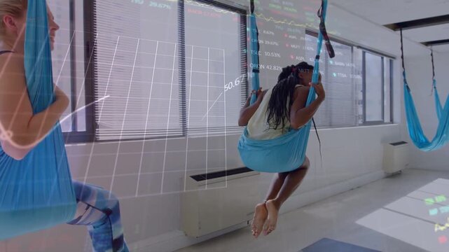 Right woman pushing off mat, pulling hammock, lifting for yoga as transparent HUD overlaying scene