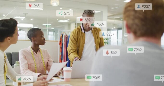 Vertical video: Leading man in mustard gesturing at laptop in office tracking reach, icons rising