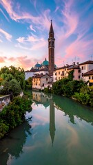 Obraz premium Tranquil river flows through a quaint town, reflecting a tower against a sunset sky