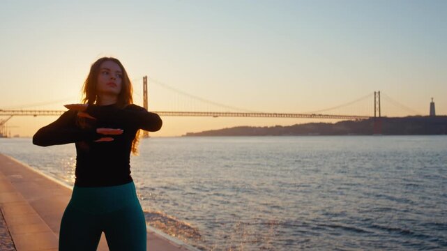 Graceful woman dancing by the river at sunset in lisbon