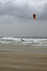 Kitesurfer at Conil de la Frontera beach. Wild autumn weather with big waves at Conil de la Frontera, Andalusia, Spain, Europe. © glashaut