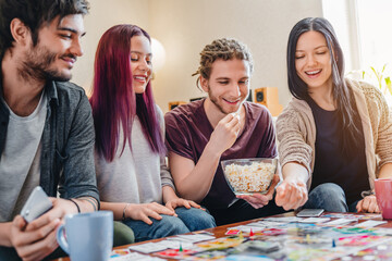 Fototapeta premium Friends gathered around table playing board game at home, smiling and competing, strategy game, indoor entertainment, fun activity, social interaction, leisure and modern lifestyle concept