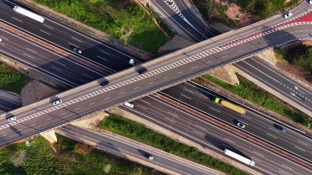 Multi-lane highway interchange with overpass, showing flowing traffic, trucks and cars navigating lanes and ramps in modern road infrastructure