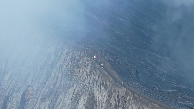 People walking on the dangerous crater rim of mount bromo volcano