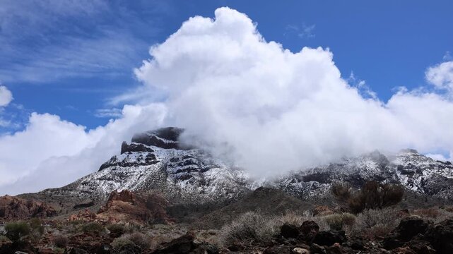 Snow covered Teide volcano landscape after storm Therese in Tenerife Canary Islands, dramatic clouds, volcanic terrain and winter conditions in subtropical island