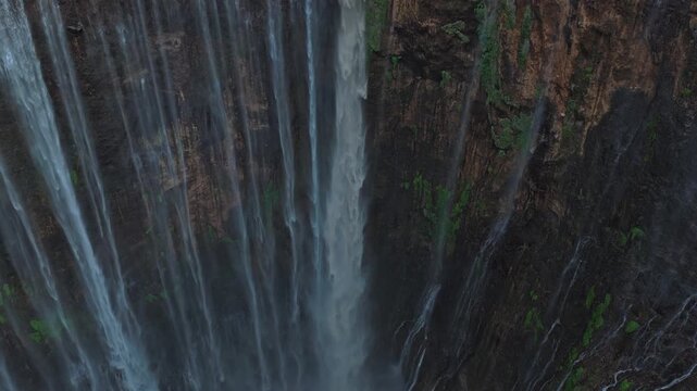Drone flying backwards from tumpak sewu waterfall in indonesia