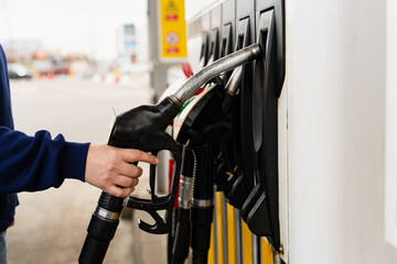 Close-up of hand holding petrol nozzle while refueling vehicle. © Rabizo Anatolii