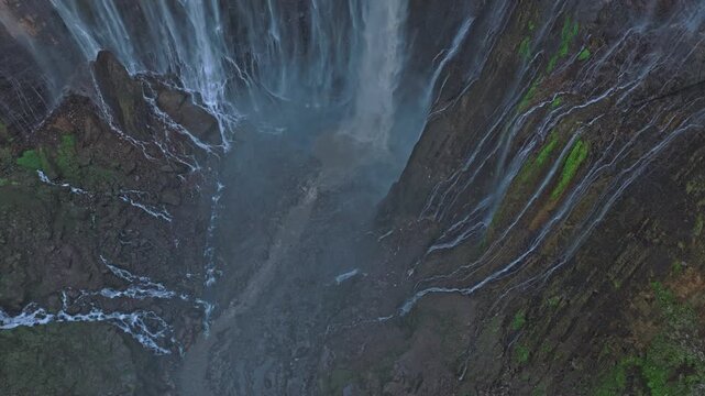 Drone flying towards majestic tumpak sewu waterfall in indonesia