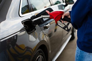 Hand refilling vehicle tank with gasoline from fuel pump. © Rabizo Anatolii