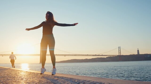 Athletic woman doing jumping jacks at sunrise in lisbon