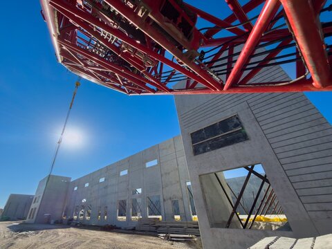 Heavy duty high-capacity lattice-boom crawler, crane parked at warehouse construction site, used for lifting large and heavy precast concrete wall panels 