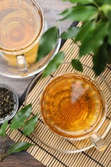 Obraz premium Refreshing green tea and dry leaves on wooden table, flat lay