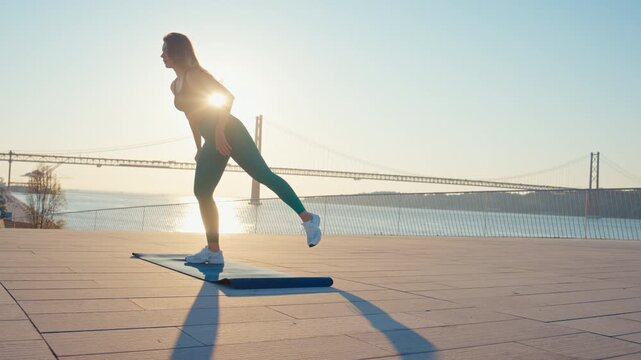 Young woman doing squats outdoor at sunrise