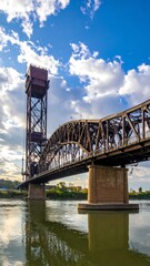 Fototapeta premium Tall drawbridge over river with clouds