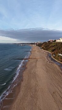 Aerial 4K view of empty Bournemouth beach and pristine coastline with turquoise waves on a sunny day, Dorset, UK