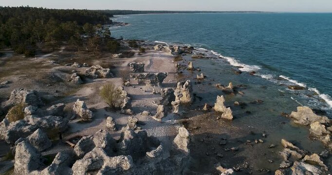 Drone pulling back over raukf&auml;lt and limestone sea stacks revealing the Folhammar coastline on Gotland, Sweden from a different angle