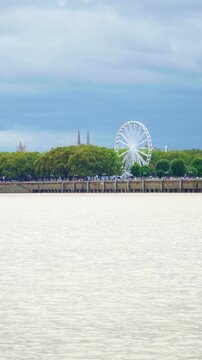 Ferris wheel turning at touristic Place des Quinconces Bordeaux by Garonne river