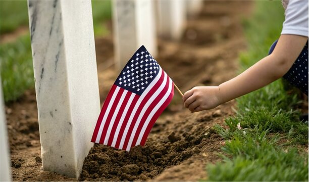 Child hand place american flag at grave in cemetery. Memorial day remembrance