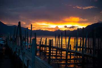Obraz premium Wooden dock at Lake Atitlán Guatemala during dramatic sunset with mountains silhouette