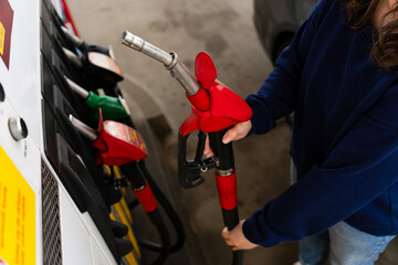 Fuel station scene with hand holding gasoline pump nozzle. © Rabizo Anatolii