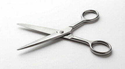 Obraz premium Metal scissors placed open on a clean white background. Soft studio lighting creating subtle shadow beneath the object