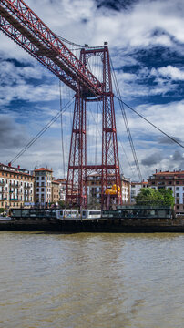 Puente de Vizcaya sobre la r&iacute;a del Nervi&oacute;n, ic&oacute;nico puente transbordador de estructura met&aacute;lica roja que une Portugalete y Getxo, bajo un cielo azul con nubes din&aacute;micas en Bizkaia.