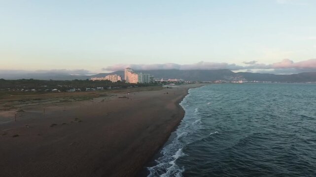 Wide drone shot of the Mediterranean coastline with mountains and clouds in the background, Empuriabrava