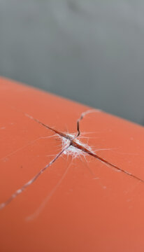 Close up of cracked orange plastic surface texture representing material damage, fragility and impact accident for construction background or quality control concept