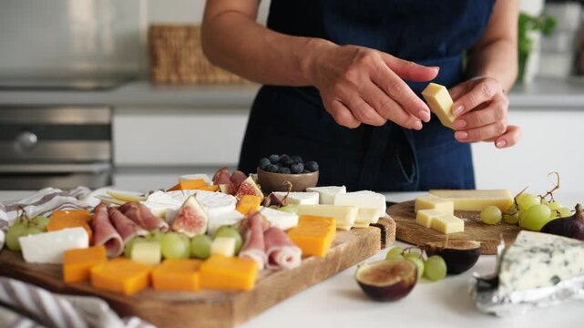 Woman Prepares A Cheese Platter With Fruits In The Kitchen And Places Parmesan Cheese On A Board For A Friend's Party