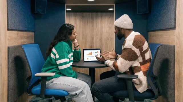 Loan officer in modern private booth engaging with client tablet displaying preapproval results from linked bank data foreground sharp background gently out of focus.