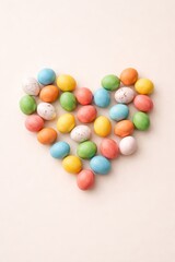 Obraz premium Top view of pastel colored Easter eggs arranged in a heart shape on a soft neutral background, minimal festive composition with gentle tones and copy space.
