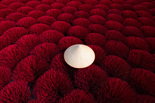 Traditional vietnamese conical hat on red incense sticks