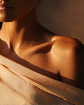 Skincare branding close-up &ndash; Warm light on woman shoulder, collarbone and lips with beige fabric