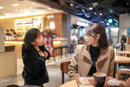 Two women converse warmly in a cozy cafe. Their smiles reflect genuine connection and comfort. Soft lighting enhances the inviting, intimate atmosphere. Ideal for scenes of friendship