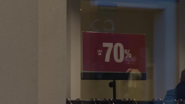 Vacant store window. Silent boutique window showcasing seventy percent discount sign amidst reflective glass surfaces