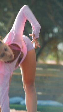 Woman performs warmup stretches in park at sunrise with vibrant attire
